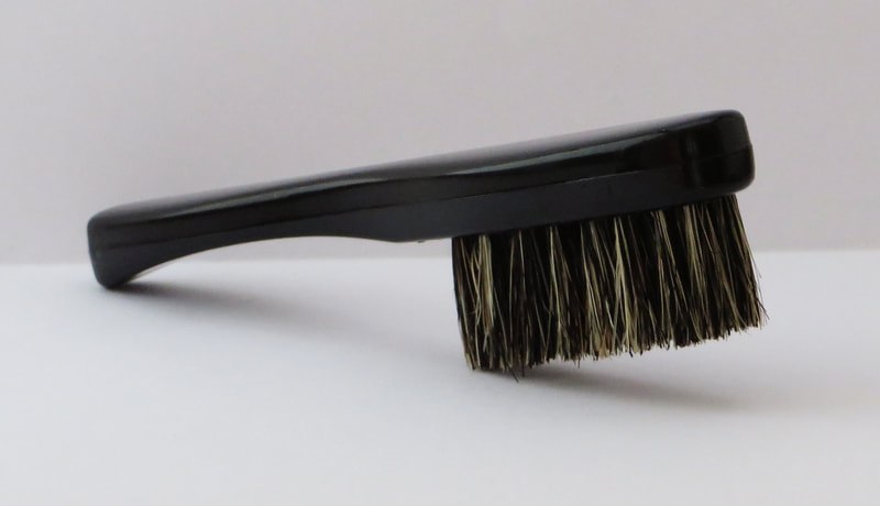 A moustache brush with a handle and natural bristles.